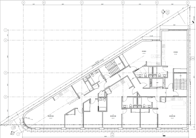 A floor plan of an irregularly shaped building shows three bedrooms, two studios, multiple bathrooms, kitchens, stairwells, and hallways.